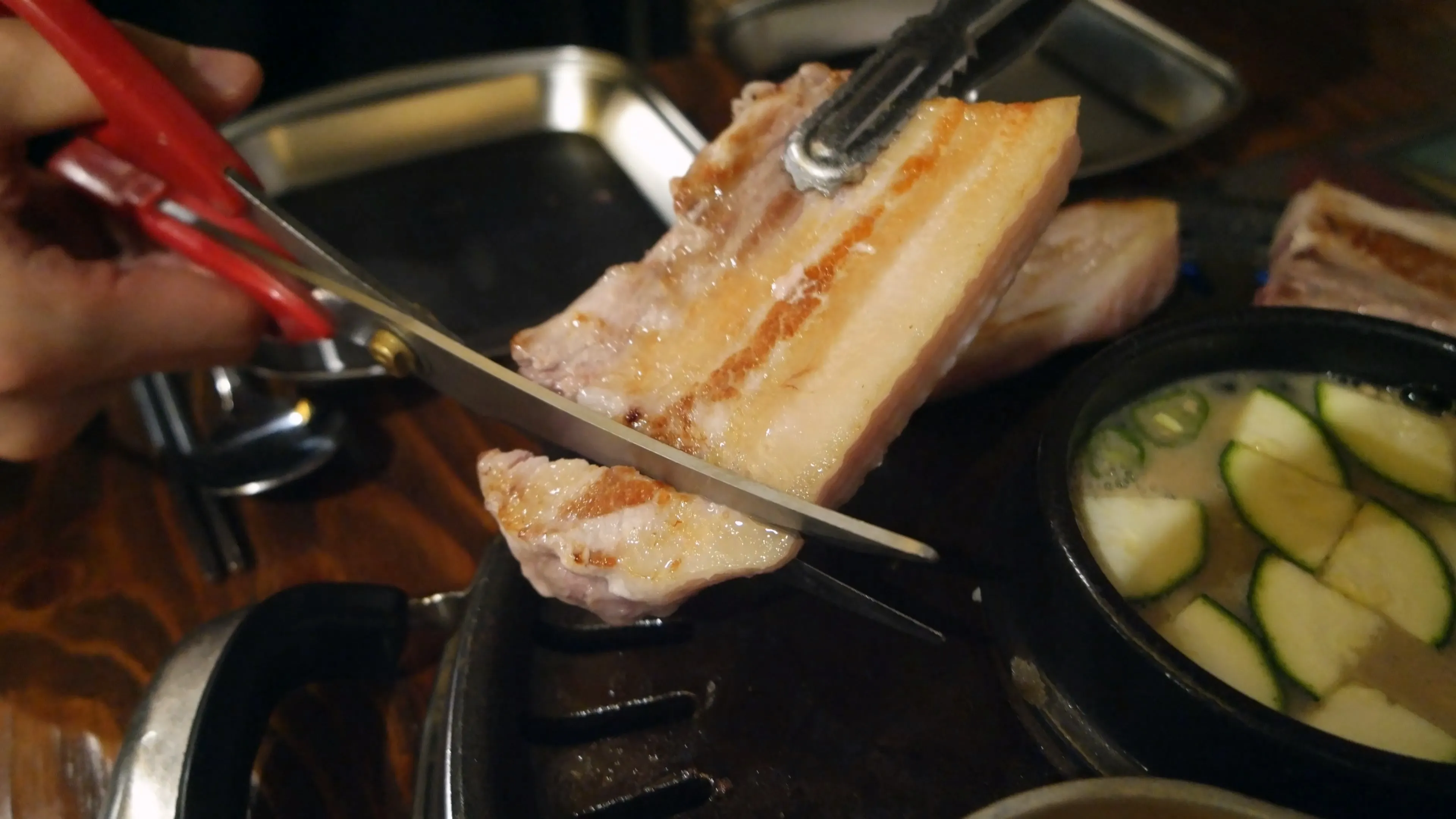 가위로 익은 삼겹살을 한입 크기로 자르는 모습