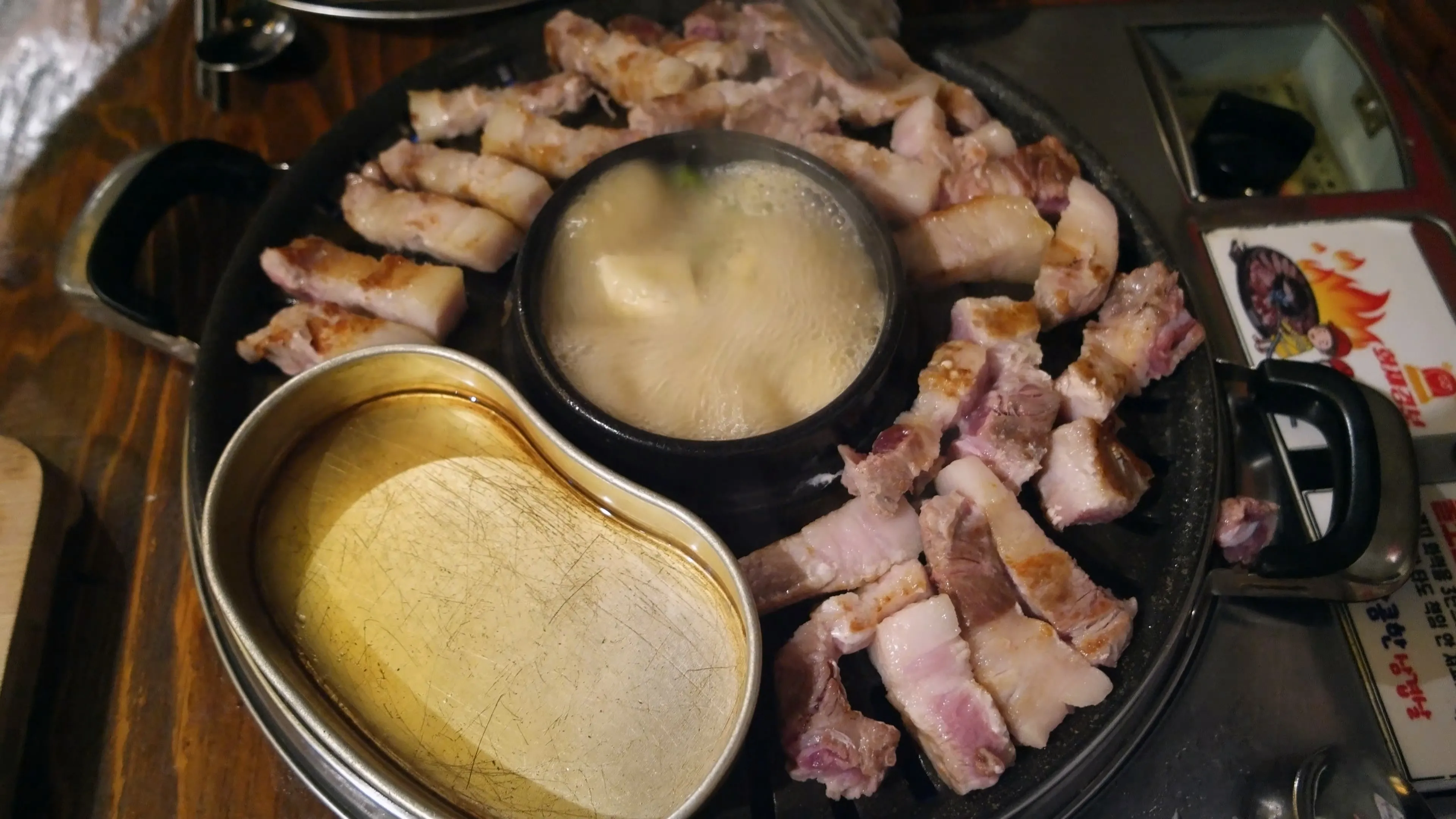 한입 크기로 잘린 삼겹살 조각들이 불판 위에 넓게 펼쳐져 골고루 익고 있는 모습